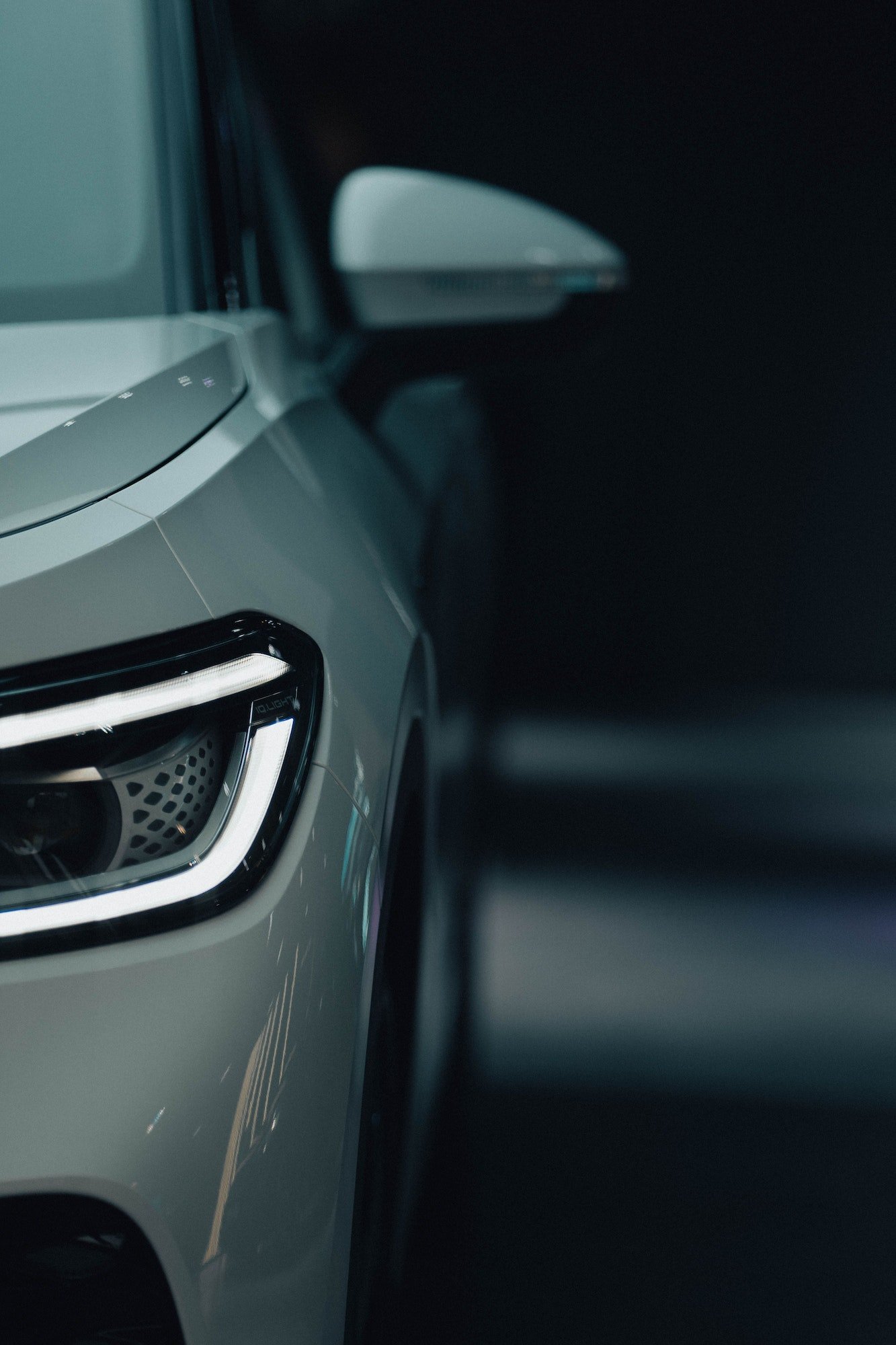 Vertical shot of the front - headlight and side mirror of white luxury car